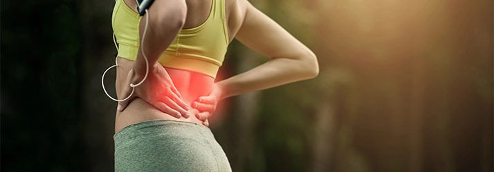 Chiropractic Quincy MA Low Back Pain A woman in sportswear holding her lower back, with the area highlighted in red to indicate discomfort or pain.