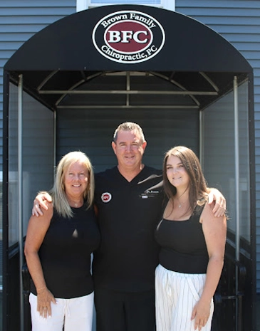 Chiropractor Christopher Brown with two woman smiling outside of the clinic.